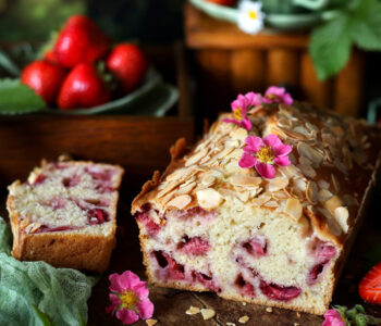 Lekkie ciasto z truskawkami – świeże owoce na cieście, otoczone dekoracją z liści i naturalnego tła.