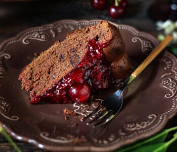 Krojone ciasto czekoladowe z wiśniami – widać idealną wilgotność i soczystą frużelinę, która przełamuje słodycz deseru.