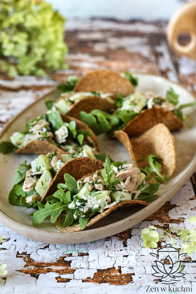 Chrupiące tacos wypełnione tuńczykiem, warzywami i świeżymi ziołami na drewnianym stole.