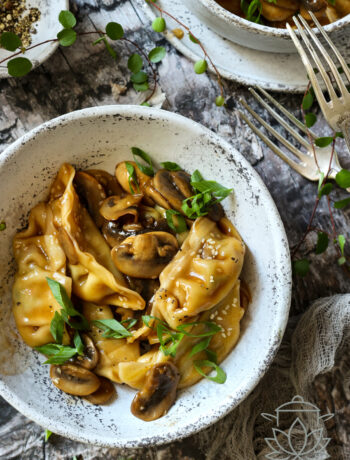 Pierożki Gyoza w sosie sojowym z pieczarkami, sezamem i świeżym szczypiorkiem podana w ceramicznej misce