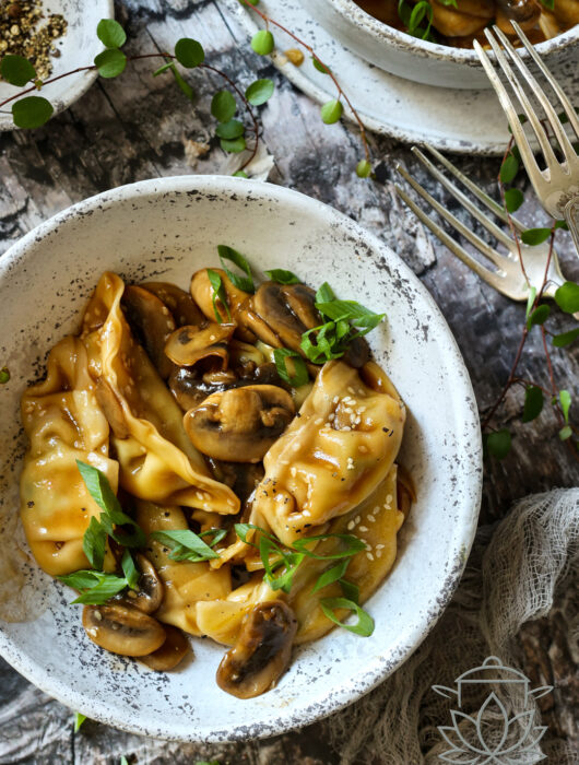 Pierożki Gyoza w sosie sojowym z pieczarkami, sezamem i świeżym szczypiorkiem podana w ceramicznej misce