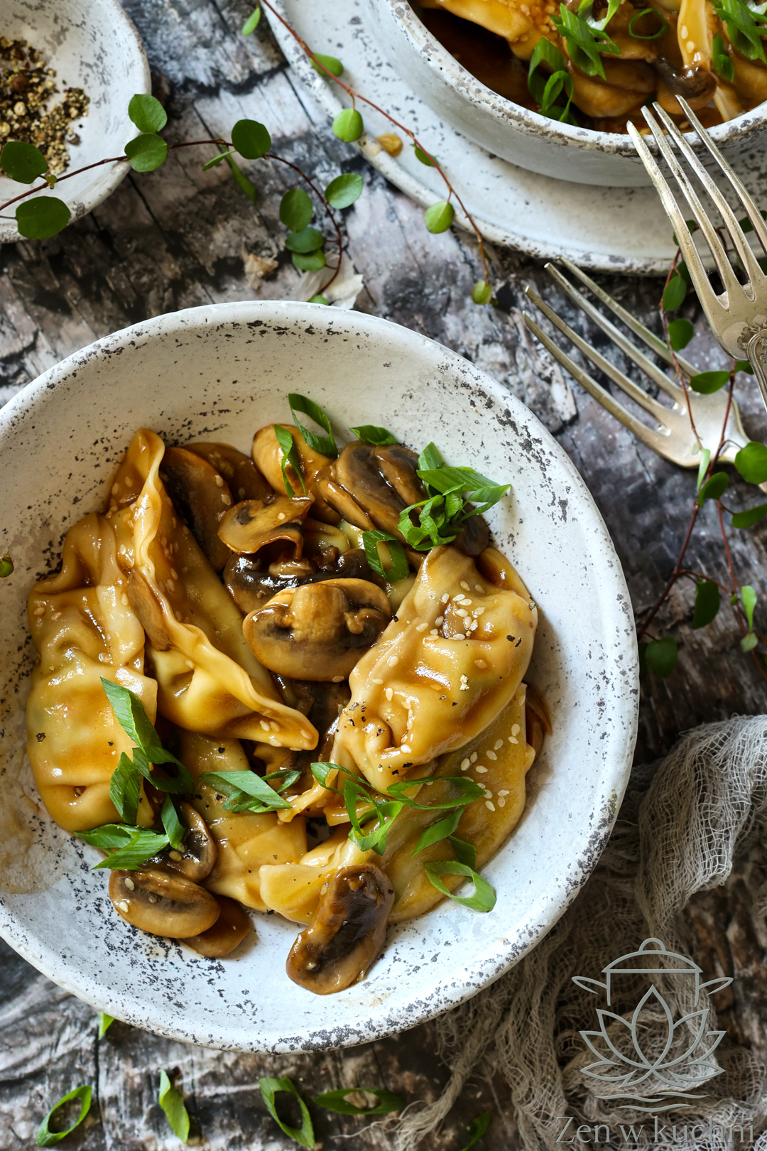 Pierożki Gyoza w sosie sojowym z pieczarkami, sezamem i świeżym szczypiorkiem podana w ceramicznej misce